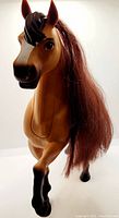 Front and side angled views of Dreamworks Just Play Spirit Talking Horse showing detailed plastic figure, brown synthetic mane, and button on hind quarter for sound