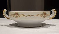 Side view of the bowl showcasing the floral design pattern and gold trim with handles.