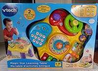 Box front image showing full view of the Vtech Magic Star Learning Table with a toddler playing and bilingual labeling in English and French.
