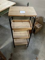 Front view of the three-shelf wooden and metal rack showing natural wood finish shelves and black metal tubular legs.