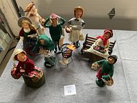 Photo showing all eight Cries of London caroler and vendor figurines arranged together on floor.