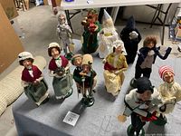 Full collection of Byers' Choice Dickens characters displayed on table, showing group arrangement and detailed costumes.