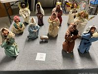 Overview of full 12 piece nativity set displayed on gray fabric surface showing angels, shepherds, kings and holy family arranged in semi-circle