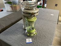 Photo showing front view of Margaritaville blender with green accented glass blending jar and control panel, along with numbered lot card on table.