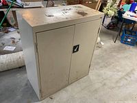 Full view of the beige metal cabinet with double doors, showing general condition and size.