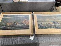 Two framed naval prints lying side by side on a grey surface showing World War II naval scenes with ships and battle action.