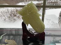 Front view of jade carving on wooden stand