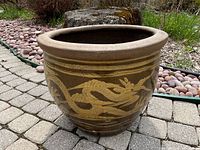Side view of round medium-sized clay planter showing detailed yellow dragon on brown glaze.