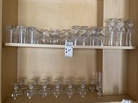 Two shelves of crystal glasses arranged on wooden shelving