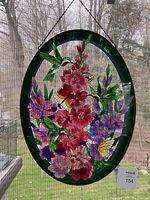 Full view of oval stained glass window against window screen with hanging chain visible