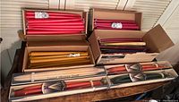 Top-down view of multiple boxes of long taper candles in red, orange, coral colors in original packaging.