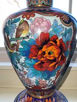 Detail view of one vase showing red and orange peony, blue foliage, and bird motif