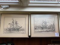 Two framed black-and-white schooner prints displayed side by side on floor under window