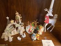 Full view of Christmas figurines including Santa, reindeer, nativity scene, Cherished Teddies bears, snowman and others arranged on a wooden shelf