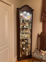 Full view of Howard Miller corner curio cabinet showing overall design, wood finish, glass panels, interior display items