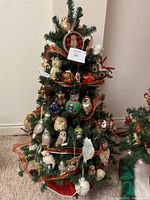 Front view of the decorated Christmas tree showing the dense arrangement of owl ornaments and orange ribbon garland.