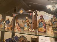 Full display of nativity set on glass shelf including stable and figurines showing color and style.