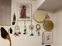 Wide shot of all wall-hung items including framed print, feathers, dreamcatchers, tambourines, and small carvings