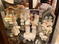 Precious Moments nativity figurines arranged together in a display cabinet, showing various characters and animals.