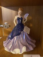 Full view of Royal Doulton porcelain figurine of a lady in a purple/blue gown holding a fan.