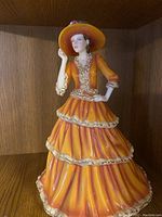 Full view of Royal Doulton Pretty Ladies Diana figurine, showing orange tiered dress and wide brim hat.