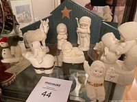 Wide view of multiple Snowbabies figurines including children in textured white outfits, a white horse, and nativity backdrop with star.