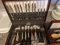 Wooden chest opened showing 12 dinner knives in lid and forks/spoons in base