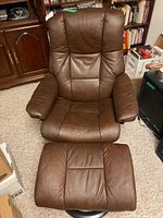 Front view of brown leather Stressless swivel recliner chair and matching ottoman