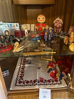 Wide shot of nesting dolls, embroidered textiles and small Ukrainian decorative items on wooden shelf.