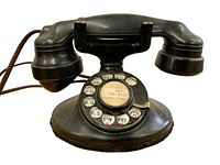 Front view of black Western Electric rotary dial phone, showing dial with letters and numbers, handset placed on cradle.