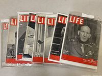 Batch of 8 Life magazines from WWII era in protective plastic sleeves, showing varying cover art and dates.