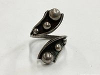Front and angled view showing oxidized sterling silver ring with six raised round orbs across two curved segments.