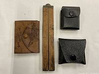 Three small pouches (one leather engraved) next to a wooden folding ruler