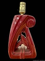 Side view of the red porcelain lamp base showing sculptural curves and scroll design.