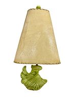 Front view of the lamp showing the beige stitched lampshade and green porcelain dancing woman base.