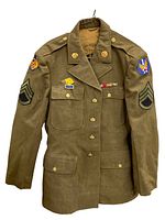 Full front view of WWII U.S. Air Forces jacket hanging, showing patches and medals.