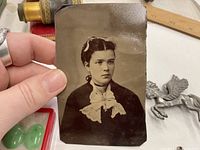 Close-up of antique photo held in hand showing young woman with dark hair and lace collar