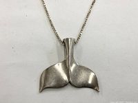 Close-up of the whale tail pendant with chain visible, showing the pendant shape and finish.