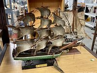 Full view of three vintage model ships showing their size, rigging, and condition.