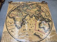Full view of the large circular 1851 Eastern Hemisphere map laid flat on a concrete floor, showing continents and oceans with some spotting and wear.