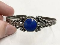 Front view of vintage sterling silver cuff bracelet with round lapis lazuli stone and ornate silver leaf design.