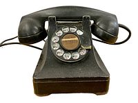 Front view of black vintage rotary dial telephone on wooden surface