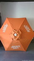 Top view of the patio umbrella showing Aperol Spritz logos on orange fabric.