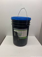 Front view of the black plastic bucket with blue lid showing label and handle