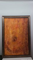 Full view of the framed oil painting showing its rectangular frame and textured warm-colored abstract composition.