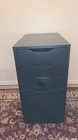 Front view of black wooden Ikea drawer unit showing three drawers with integrated handle cut-outs.