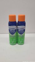 Front view of two Microban 24 Hour Sanitizing Spray cans with orange caps, blue and green labels.