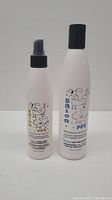 Two white bottles with cartoon dog illustrations; one spray bottle conditioner and one shampoo bottle, both 240ml.