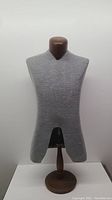 Front view of mannequin torso showing gray fabric cover, V-cut front neckline, and solid oakwood base with neck stand.