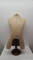 Front view of beige fabric covered mannequin torso on round oakwood base